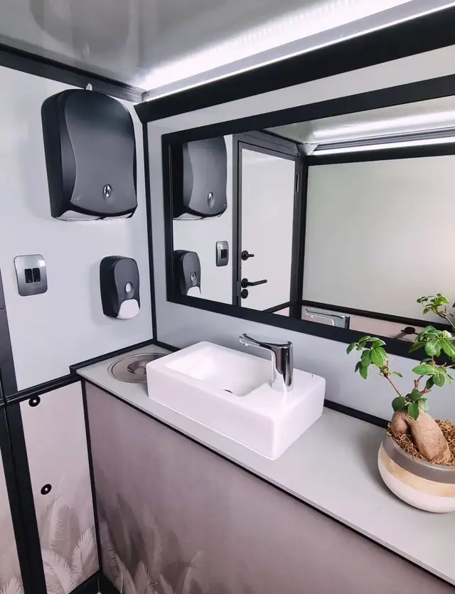 Restroom trailer vanity with vessel sink, mirror and soap dispensers