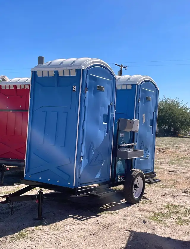 Porta potties on a towable trailer at an open jobsite