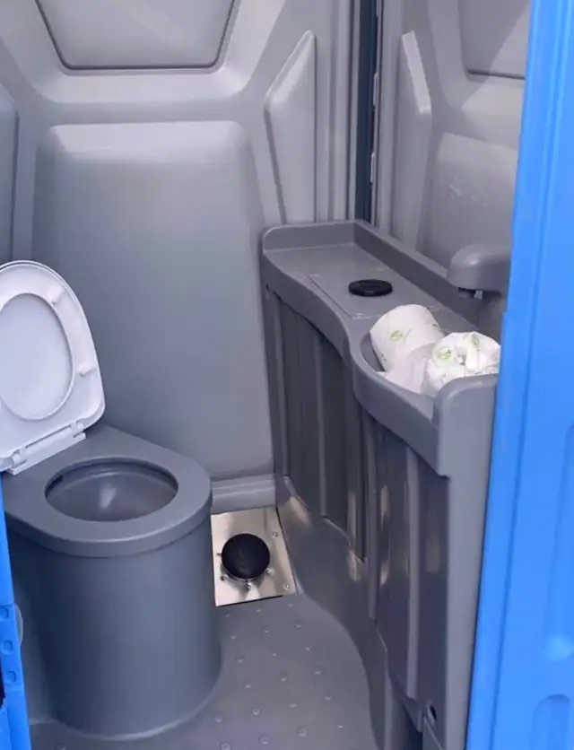 Deluxe porta potty interior with flushing toilet and hand-wash sink