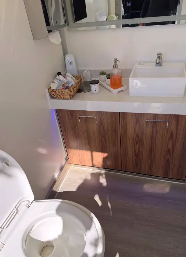 Luxury restroom trailer vanity with wood cabinets and vessel sink