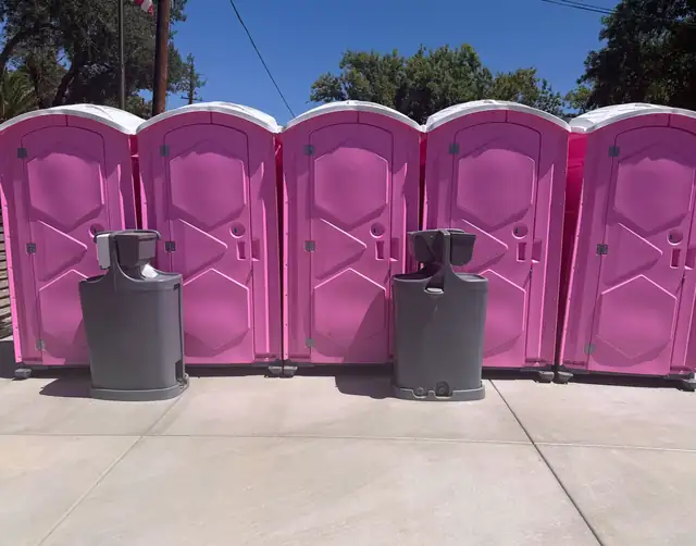 Row of pink porta potties with two handwashing stations for an event