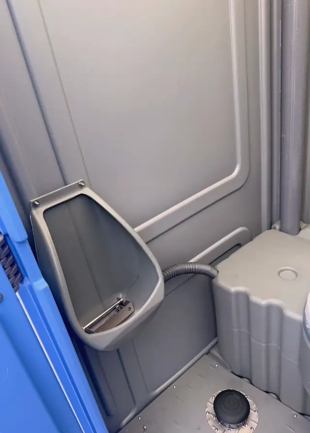 Porta potty interior showing urinal and anti-slip floor