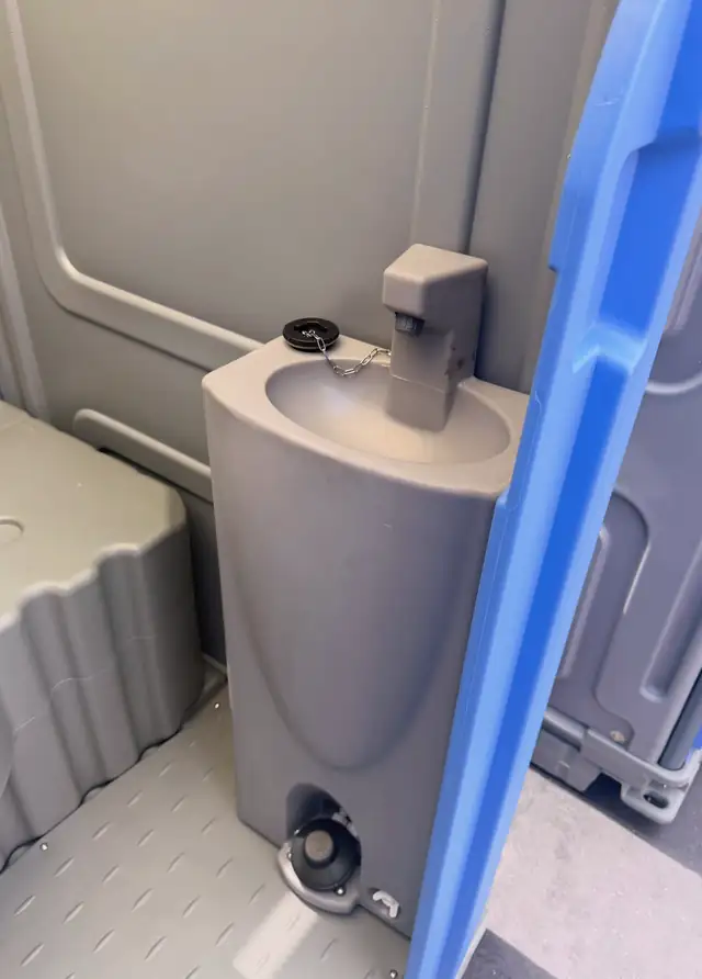 Porta potty interior with built-in hand-wash sink and soap