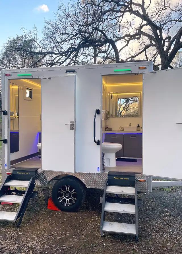 Luxury restroom trailer with both doors open and interior lights on
