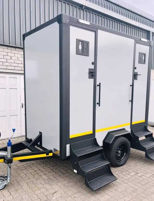 Two-stall restroom trailer with separate men's and women's doors and fold-down steps
